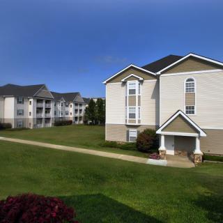 A view of apartment buildings with a well-maintained lawn under a clear blue sky.