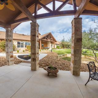 A spacious outdoor patio featuring stone pillars and a landscaped garden.
