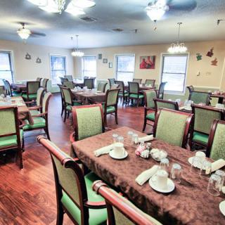 A spacious dining room with neatly arranged tables and comfortable chairs, elegantly set for guests.