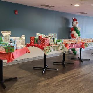 A festive setup featuring decorated tables filled with Christmas gifts ready for an event.