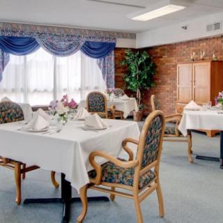 An elegant dining room with tables set for a meal, featuring ornate chairs, decorative curtains, and soft lighting.