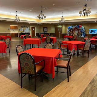 A spacious dining area featuring red tablecloths and decorative chandeliers.
