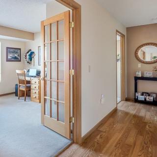 A cozy home interior featuring a hallway with wooden flooring leading to an office space through a French door.