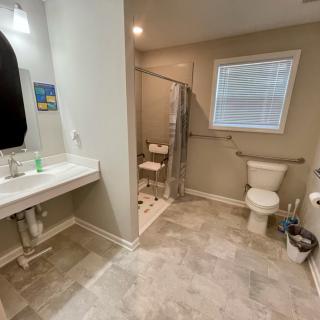 A modern, accessible bathroom with a walk-in shower, toilet, and sink.