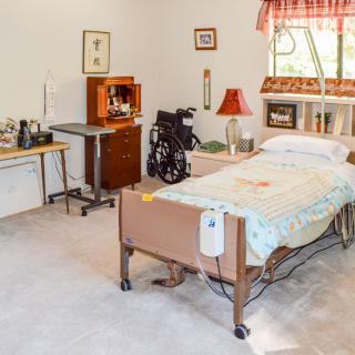A care facility room with a hospital bed and wheelchair.