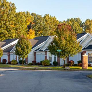 A suburban neighborhood street lined with trees and houses during autumn.