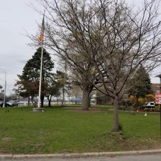 A peaceful park setting featuring a flagpole and trees on a cloudy day.