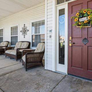 A welcoming porch with comfortable chairs and a sunflower wreath on the front door.