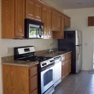 A modern kitchen featuring wooden cabinets, a stove, microwave, and refrigerator.