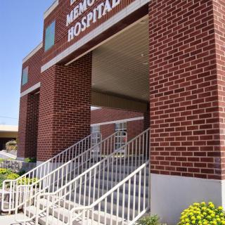The brick exterior of a hospital with stairs leading to the entrance.
