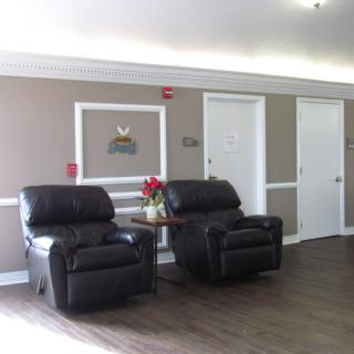 A cozy waiting area with two leather recliners and a small table with flowers.
