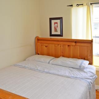 A cozy bedroom with a wooden headboard and natural light from a nearby window.
