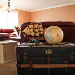 A cozy living room featuring a vintage trunk with a globe and model ship as decorative pieces.