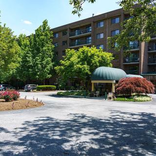 A hotel entrance with a tree-lined driveway and well-maintained landscaping.