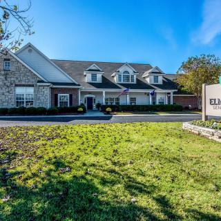 A suburban residential house with a well-maintained lawn and clear blue sky.