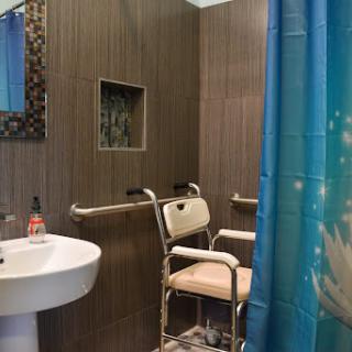 A modern, handicap-accessible bathroom featuring a shower area with safety rails and a sink.