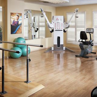 A fitness room equipped with various exercise machines and equipment, including exercise balls and parallel bars.