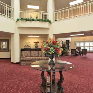 A spacious lobby area featuring elegant decor and furniture, with a central table displaying a floral arrangement.