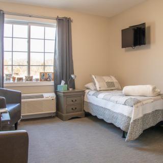 A cozy bedroom with a single bed, nightstand, and wall-mounted TV.