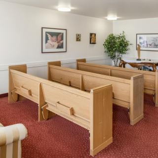 A small chapel interior with wooden pews and religious decor.