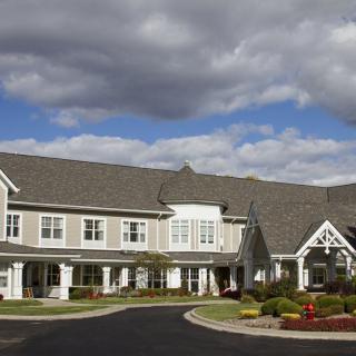 A large building with a landscaped front yard under a cloudy sky.