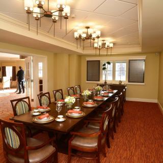 A formal dining room with an elegantly set long table and chandeliers.
