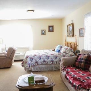 A cozy bedroom with a bed, armchairs, and a sofa in a well-lit space.