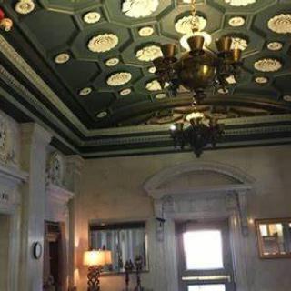 A vintage interior with ornate ceiling designs and a central chandelier.