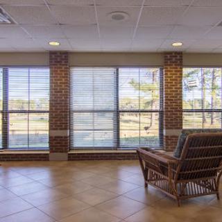 A serene lobby area featuring large windows that invite natural light, complemented by a stylish seating arrangement against a brick wall.
