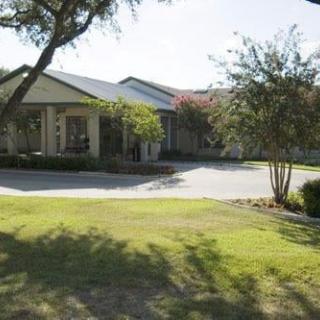 A residential house with a driveway, surrounded by trees and a well-maintained lawn on a sunny day.