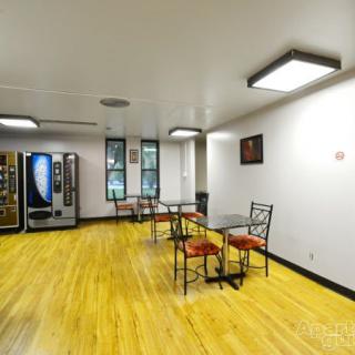 A break room with vending machines, tables, and chairs on a wooden floor.