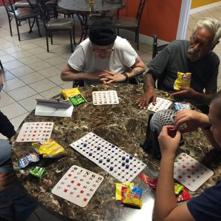 A group of people playing bingo together at a table indoors.