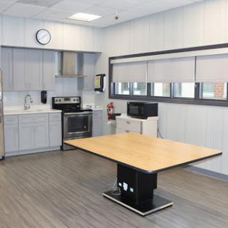 A modern kitchen breakroom featuring a central table and essential appliances.