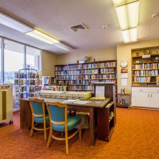 A cozy library reading room with shelves of books and a table with chairs.
