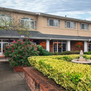 A two-story building with a well-maintained garden and a fountain at the entrance.