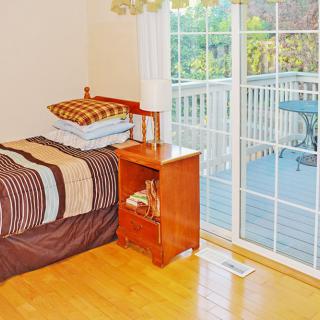 A cozy bedroom with a bed, nightstand, and a sliding glass door leading to a balcony.