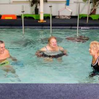 Three people participating in an indoor aquatic exercise session.