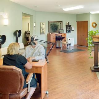 An interior view of a beauty salon with a client receiving a manicure.