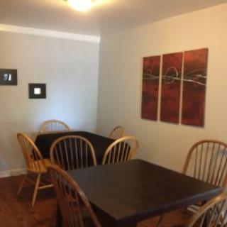 A cozy dining area with wooden tables and chairs, adorned with modern artwork on the wall.