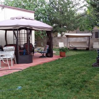 A cozy backyard with a gazebo and swing chair, surrounded by lush grass.