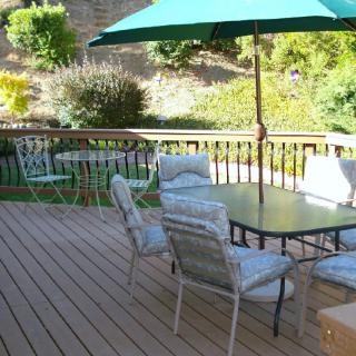 A serene outdoor patio with a dining set and umbrella on a sunny day.