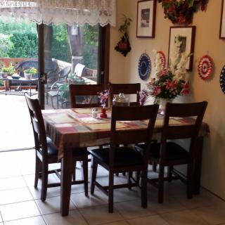 A cozy dining area with a wooden table set for six, surrounded by decorative wall plates and paintings.