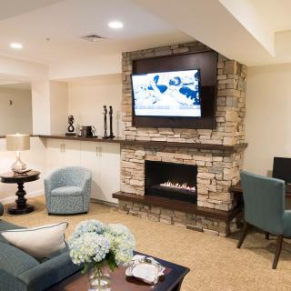 A cozy living room with a stone fireplace and modern seating, complemented by a mounted television.
