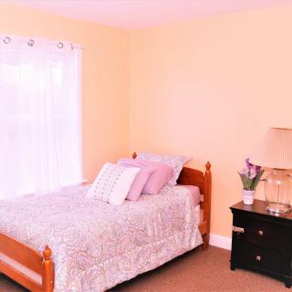 A cozy bedroom with a wooden bed, nightstand, and soft lighting.