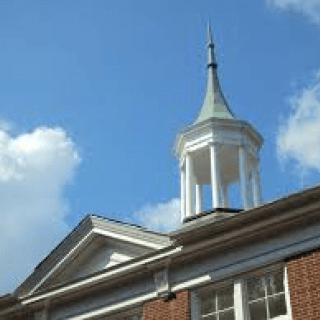 A view of a building's cupola against a blue sky.