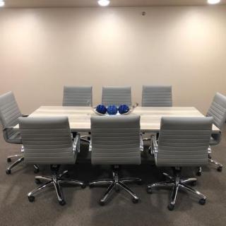 A modern conference room with a sleek meeting table and comfortable office chairs.