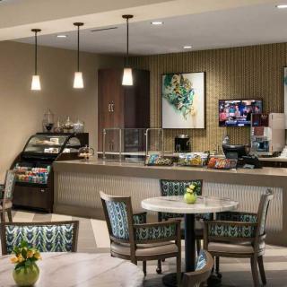 A cozy cafe interior with tables, chairs, and a service counter.