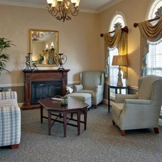 A cozy living room with elegant armchairs, a wooden coffee table, and a decorative fireplace.