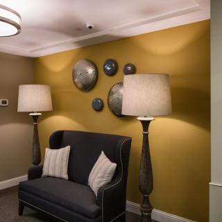 A cozy living room corner with a dark sofa, floor lamps, and circular wall decor.