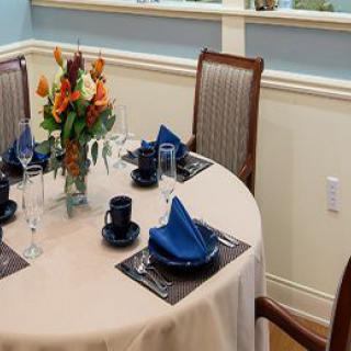 A formally set dining table with a centerpiece and blue napkins.